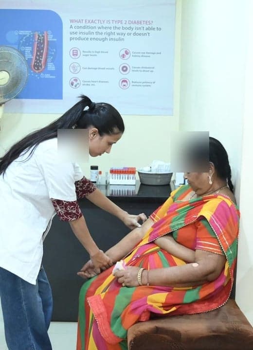 A technician collecting a blood sample from a patient at the Niramay Clinics laboratory